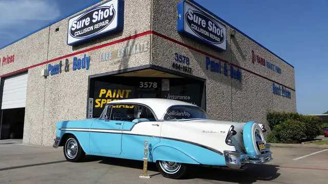 A turquoise and white classic Chevrolet Bel Air parked under the Sure Shot Collision Repair sign at the shop on Forest Lane